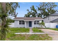 Charming single-story home with a blue door, grey facade, mature landscaping, and a driveway at 2311 16Th S Ave, St Petersburg, FL 33712