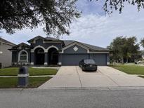 Beautiful single-story home featuring a three-car garage, dark gray exterior, and well-manicured lawn at 4217 Balington Dr, Valrico, FL 33596