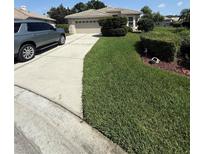 Well-manicured front yard with lush green lawn, mature landscaping, and a two-car garage at 5811 White Oak Bayou Ct, Bradenton, FL 34203
