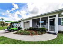 Charming home exterior featuring a well-manicured lawn, lovely landscaping and a golf cart parked in the driveway at 717 Pinewood Dr, Dunedin, FL 34698