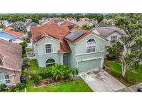 Two-story house featuring a red roof, a two-car garage, solar panels and tropical landscaping at 9707 Kings Canyon Pl, Tampa, FL 33634