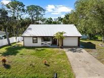 Charming single-story home with a metal roof, fresh white siding, and attached two-car garage at 116 Hermes Rd, Venice, FL 34293