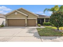 Inviting home with a two-car garage, well-maintained lawn, and lush landscaping at 12117 Streambed Dr, Riverview, FL 33579
