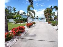 Charming single-story home featuring a spacious driveway, lush landscaping, and a welcoming front porch at 15817 Redington Dr, Redington Beach, FL 33708