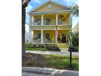Charming two-story home with a double porch, light yellow siding, white columns and trim, and a well-manicured lawn at 16014 Palmettorun Cir, Lithia, FL 33547