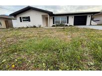 Charming single-story home featuring a black roof, white stucco, black shutters and a front yard ready for landscaping at 1703 Ironwood E Ct, Oldsmar, FL 34677