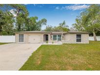 Charming single-story home featuring stone accents, a well-manicured lawn, and a two-car garage at 7607 New York Ave, Hudson, FL 34667