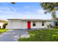 Charming single-story home featuring a red front door and a well-maintained front yard, offering great curb appeal at 1018 Osprey Ct, Dunedin, FL 34698