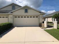 Beige garage and concrete driveway of a one-story home, with white trim and updated windows at 11439 Cambray Creek Loop, Riverview, FL 33579
