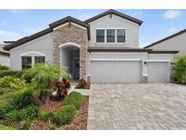 Charming home with a stone accent wall, three-car garage, and a beautiful landscaped yard at 12928 Twin Bridges Dr, Riverview, FL 33579