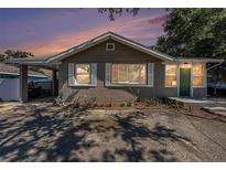 Charming single-story home featuring a covered parking, inviting green door, and lovely front garden at 1432 San Juan Ct, Clearwater, FL 33756
