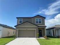 Two-story home featuring gray siding, a two-car garage, well-maintained lawn, and simple landscaping at 35233 White Water Lily Way, Zephyrhills, FL 33541