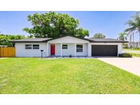 Charming single-story home featuring a red front door, well-manicured lawn, and an attached garage at 800 S Belcher Rd, Clearwater, FL 33764