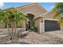 Charming home features stone accents, lush landscaping, and a quaint bench, creating an inviting entrance at 8620 Sandy Plains Dr, Riverview, FL 33578