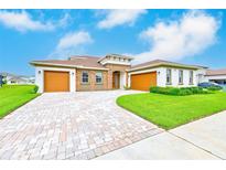 Beautiful single-Gathering home showcasing a paver driveway, three-car garage, and manicured lawn at 8717 Sanders Tree Loop, Wesley Chapel, FL 33545