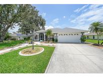 Charming single-story home featuring a well-manicured lawn, mature trees, and a two-car garage at 2226 Charleston Park Dr, North Port, FL 34287