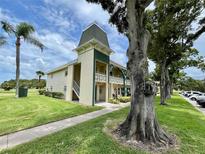 Charming condo building featuring a tower, manicured lawn, and mature trees creating a tranquil setting at 2400 Franciscan Dr # 28, Clearwater, FL 33763