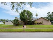 Charming single-story home with stucco exterior, stone accents, mature landscaping, and a lush green lawn at 2421 Eagle Chase Dr, Palm Harbor, FL 34683