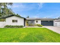 Charming single-story home with a well-manicured lawn, yellow door, and a two-car garage at 3436 Manatee Se Dr, St Petersburg, FL 33705