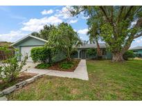Charming single-story home with a well-manicured lawn, mature trees, and inviting landscaping at 911 Sago Palm Way Way, Apollo Beach, FL 33572
