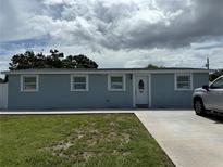 Single-story home with a light blue exterior, well-maintained lawn, and a concrete driveway at 2927 W Henry Ave, Tampa, FL 33614