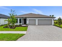 Beautiful single-story home with a gray exterior, a three-car garage, and a brick paver driveway at 2743 Winding Creek Trl, North Port, FL 34289