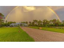 Beautiful home featuring a long drive, pristine lawn, and a vibrant rainbow in the background at 9016 Falcon Ct, Venice, FL 34293