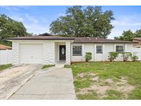 Charming single-story home features a stone accent wall, attached garage and inviting front lawn at 4410 Lurline Cir, Tampa, FL 33610