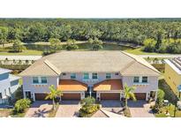 Aerial view of modern townhouses with tile roofs and attached garages, near a pond at 7730 Hidden Creek Loop # 101, Lakewood Ranch, FL 34202