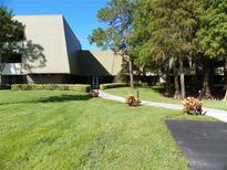 Exterior view of condo building with landscaped lawn and walkway at 36750 Us Highway 19 N # 04239, Palm Harbor, FL 34684