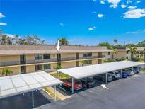 Exterior of condo building featuring carport parking under a blue sky with white clouds at 12300 Vonn Rd # 3204, Largo, FL 33774