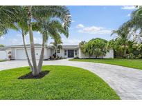 Charming home featuring lush landscaping, a circular driveway, and vibrant green lawn at 170 98Th N Ave, St Petersburg, FL 33702