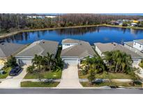 Stunning aerial view of a well-maintained home by a lake with lush landscaping and mature palm trees at 2427 Portico St, Odessa, FL 33556