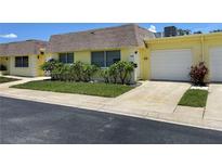 Bright yellow house with a double-car garage and landscaping at 7057 Versailles N # 15, Pinellas Park, FL 33781