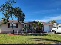 Single story home with a brick facade, mature tree, and a two-car garage at 1153 Tamarac Dr, Holiday, FL 34690