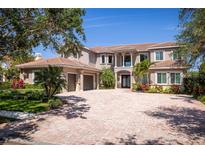 Elegant two-story home featuring a brick driveway, meticulously landscaped yard, and a neutral-toned exterior at 898 Skye Ln, Palm Harbor, FL 34683