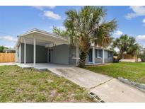Charming single-story home with a covered carport, mature landscaping, and a concrete driveway leading to the entrance at 2305 N Tampania Ave, Tampa, FL 33607