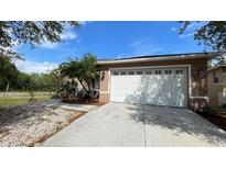 House exterior with a two car garage and landscaping at 1823 Twilight Tides St, Tarpon Springs, FL 34689