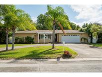 Ranch-style home with a two-car garage and lush landscaping at 2045 Golf View Dr, Dunedin, FL 34698