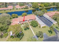 A serene aerial view shows the condo with a tile roof, adjacent to a tranquil lake and convenient parking at 9543 86Th Ave # 9543, Seminole, FL 33777
