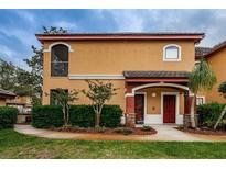 Two-story townhome with a red door, landscaping, and a walkway at 2200 Tuscany Trce # 1714, Palm Harbor, FL 34683