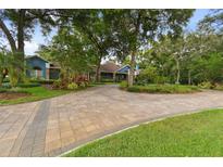 Stunning home with a long, curved brick driveway and lush, mature landscaping, creating great curb appeal at 3204 Polo Pl, Plant City, FL 33566
