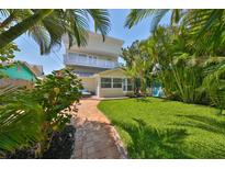 Charming home with a manicured backyard, brick pathway, and tropical landscaping at 13004 Boca Ciega Ave, Madeira Beach, FL 33708
