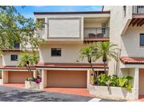 Condo building exterior featuring a two car garage, balcony, and desert landscaping at 240 Windward Psge # 602, Clearwater Beach, FL 33767