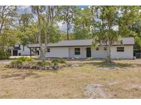 Charming single-story home featuring a fresh white exterior, dark roof, and well-maintained landscaping at 7414 Van Dyke Rd, Odessa, FL 33556