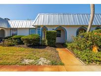 Exterior view of a condo with a metal roof and landscaped yard at 4239 Tamargo Dr, New Port Richey, FL 34652