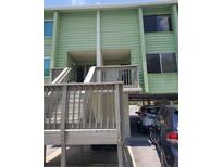Light green exterior of a two-story building with wooden stairs and parking at 318 Windrush Blvd # 9, Indian Rocks Beach, FL 33785