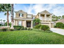 Two story house with tan exterior, landscaping and palm trees at 27922 Boreal Loop, Wesley Chapel, FL 33544