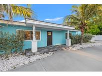 Charming blue single-story home featuring a paved entryway, white columns, and lush, tropical landscaping at 6465 30Th S St, St Petersburg, FL 33712
