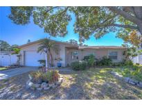 Charming ranch house with mature landscaping and a white garage door at 9252 81St Ave, Seminole, FL 33777